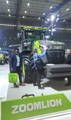 KCCIMA delegate standing beside a Zoomlion tractor at an indoor exhibition